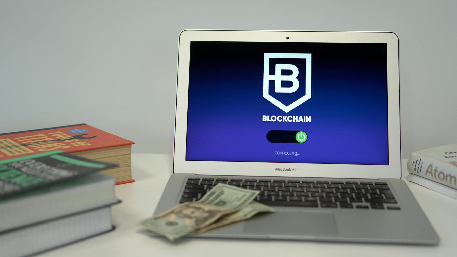 Laptop showing blockchain connection screen on desk with books and US dollars. on Quest on Chain