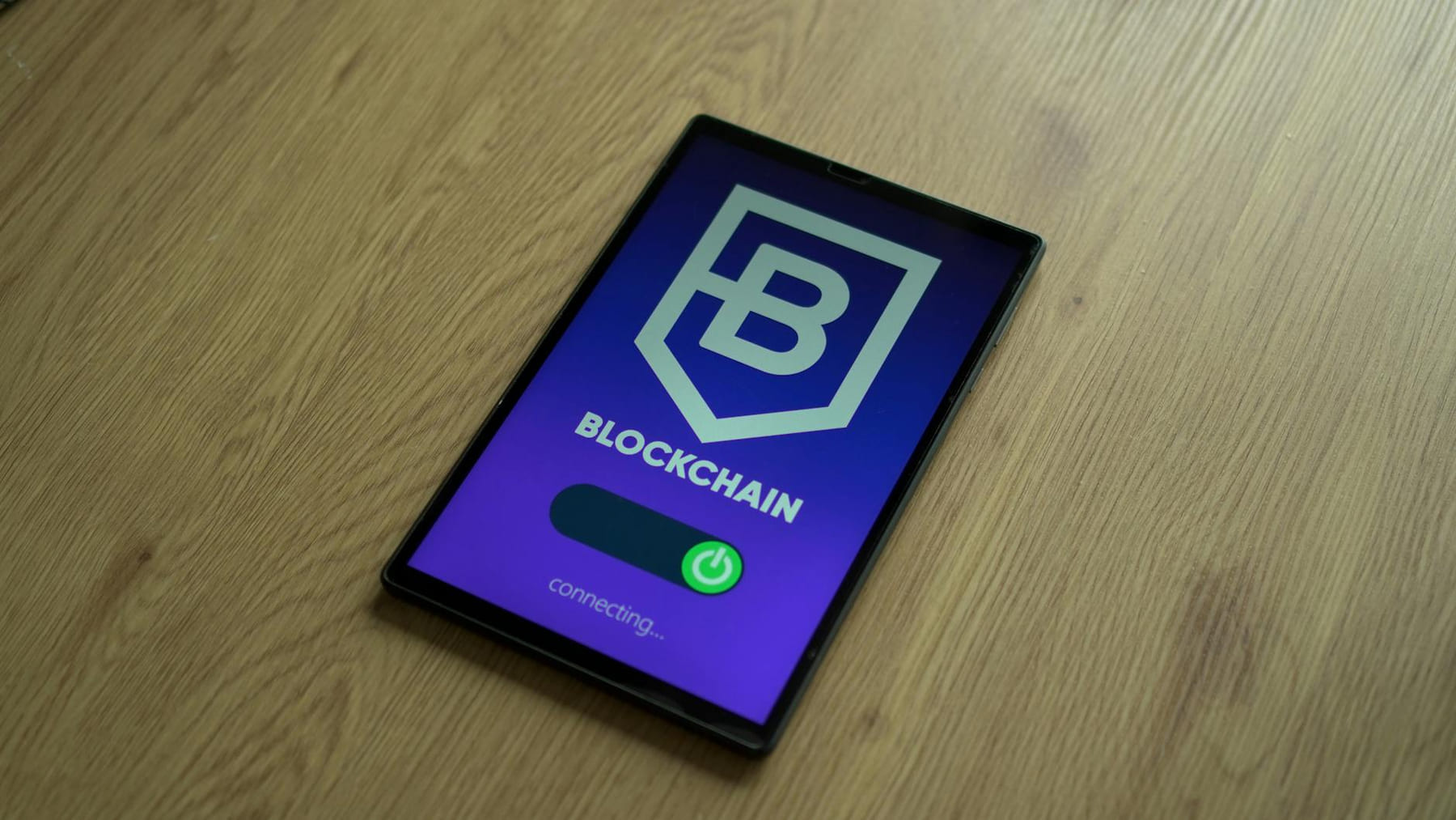 Close-up of a digital tablet showing a blockchain concept screen on a wooden surface. on Quest on Chain