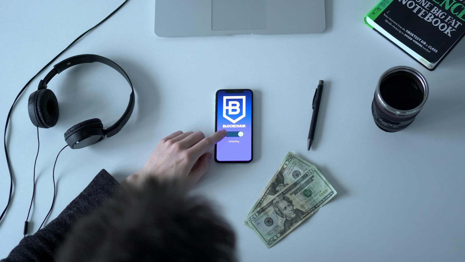 Overhead view of blockchain app on smartphone with cash, headphones, and notebook. on Quest on Chain