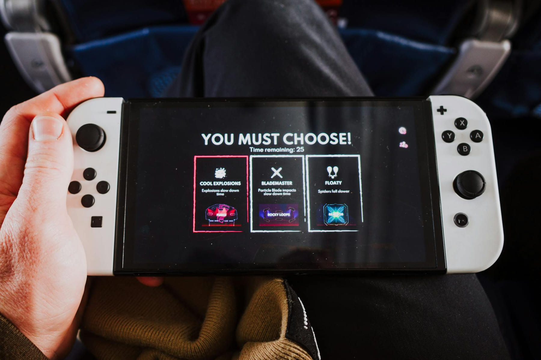 Close-up of a person holding a gaming console with an on-screen decision prompt. on Quest on Chain