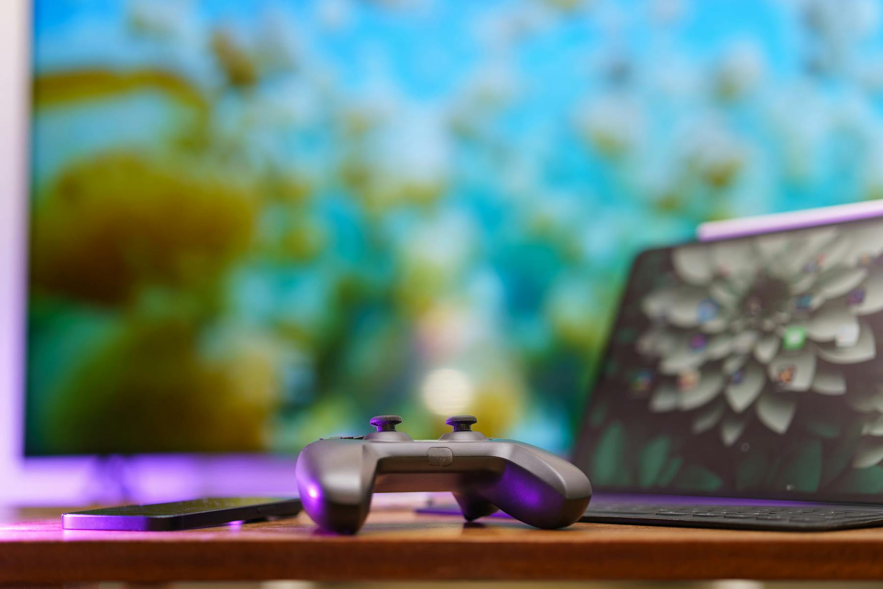 A modern gaming setup featuring a controller, laptop, and vibrant TV screen in a cozy home environment. on Quest on Chain