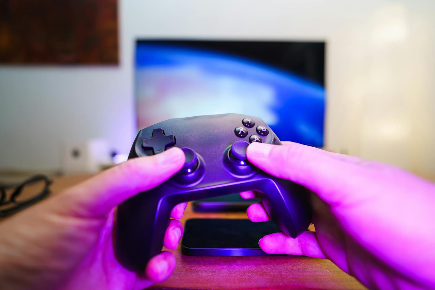 Close-up of hands holding a game controller in front of a TV screen. Perfect for entertainment setups. on Quest on Chain