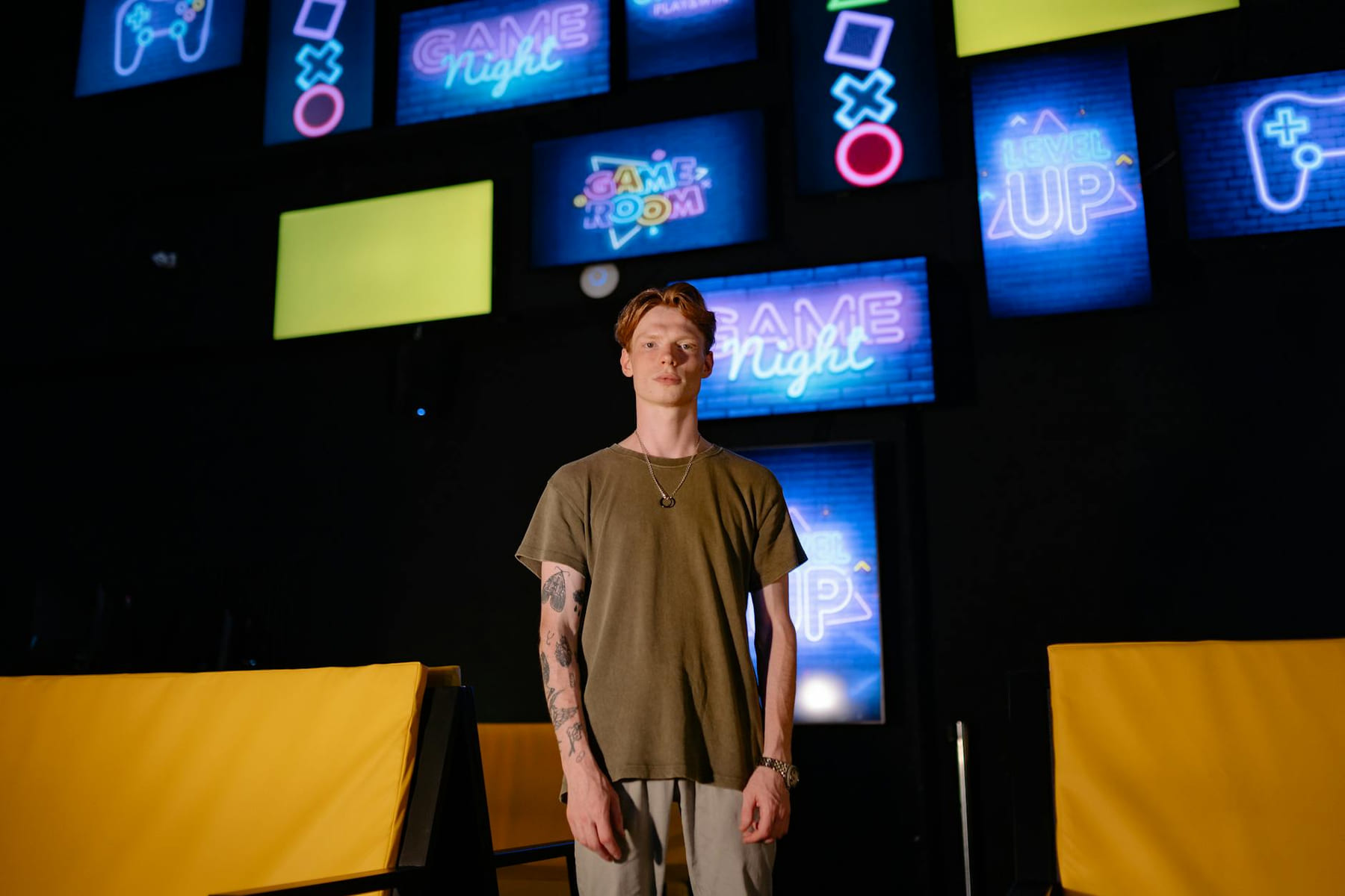A young man stands in a game room, surrounded by colorful neon signs. on Quest on Chain