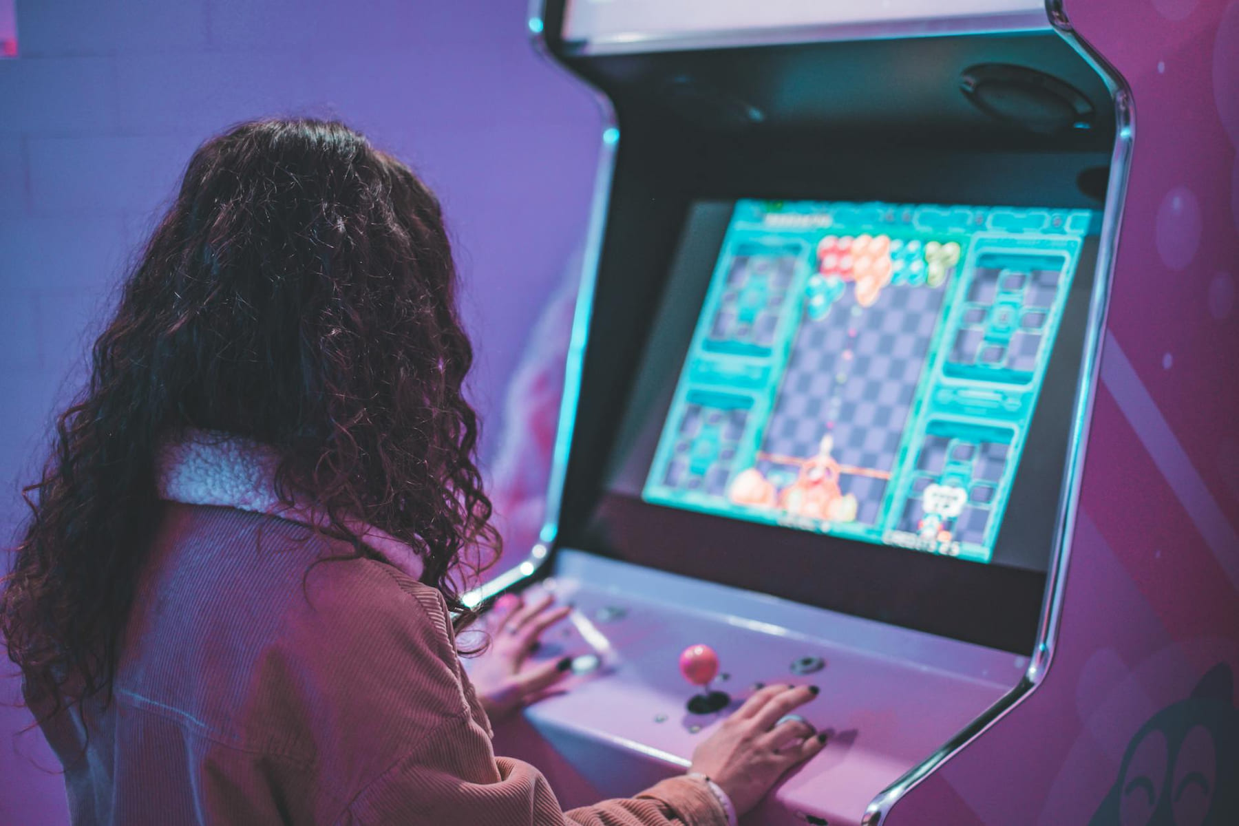A woman enjoys a nostalgic moment playing a classic arcade machine indoors. on Quest on Chain
