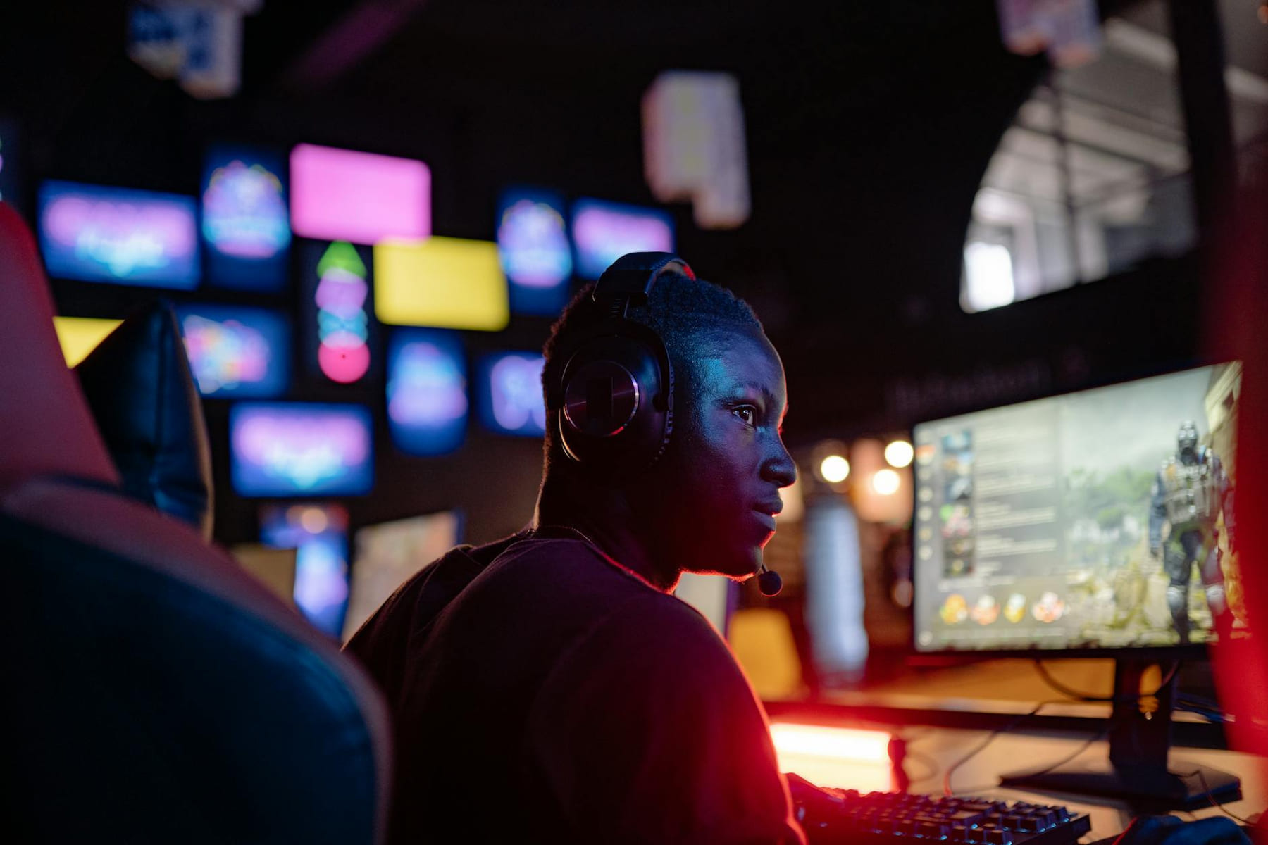 A young man intensely focused on a gaming session at a colorful gaming setup, wearing headphones. on Quest on Chain